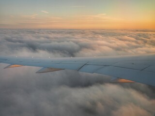 Travel: airplane wing and sunrise above the clouds, as seen from a passenger airplane