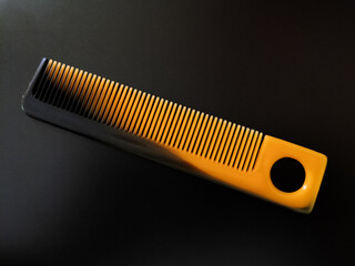 Black and orange plastic comb isolated ion black background
