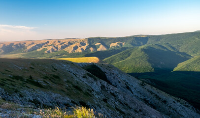Pid to the surrounding mountains from the lower plateau of Chatyr-Dag in Crimea in the light of the setting sun.