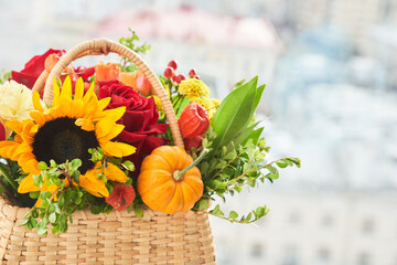 Mixed autumn flowers, sunflower, pumpkin, rose, physalis in basket, bouquet is on the windowsill...