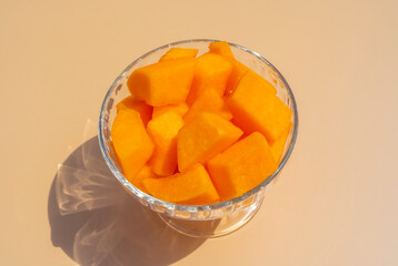 Cantaloupe fresh melon cubes in glass bowl on beige background. Organic vegetarian healthy food. Diet dessert fruit.