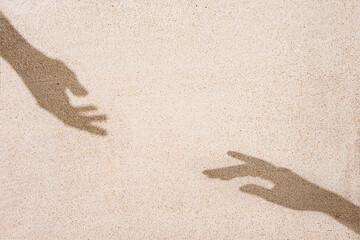 Shadows of two elegant hands on sand background, copy space