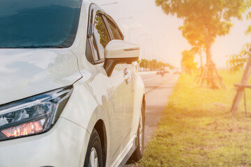 White cars parked on the roadside with natural light in the background.