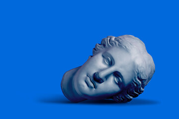 Composition with gypsum greek goddess plaster head on blue background, sleeping beauty concept - obrazy, fototapety, plakaty