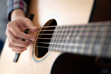 Woman's hands playing acoustic guitar, close up