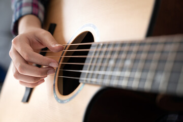 Fototapeta premium Woman's hands playing acoustic guitar, close up