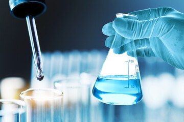 hand of scientist holding flask with lab glassware in chemical laboratory background, science...