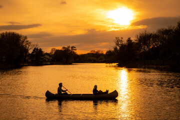 Silhouette of couple with dog kayaking in the lake at sunset