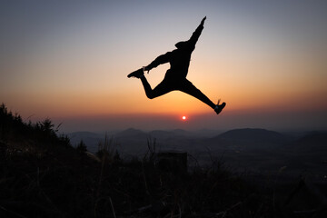 Silhouette of a teenager and an athlete trains explosiveness and tries to jump as high as possible...
