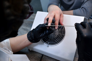 close-up manicurist removes the old coating on the nail plate wearing black gloves. Self care authentic. The concept of beauty professional nail care