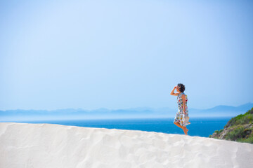 Obraz na płótnie Canvas happy woman with a colored dress on a white sandy beach