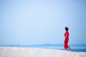 happy woman with a red dress on a white sandy beach