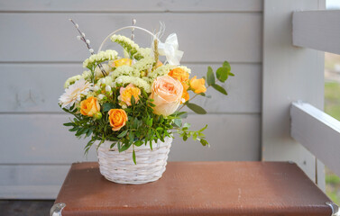 a beautiful bouquet of fresh flowers in a basket on a vintage suitcase on a gray wall background