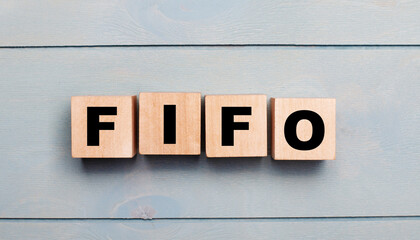 Wooden cubes with the text FIFO First In, First Out on a light blue wooden background.