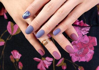 Fototapeta premium Beautiful womans hand with purple matte manicure on fabric