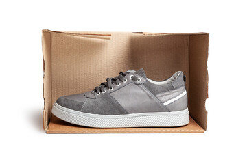 Grey casual sports shoes/sneaker in a brown cardboard box isolated on a white background