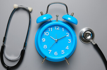 A picture of clock and stethoscope on grey background. Healthcare check up time.