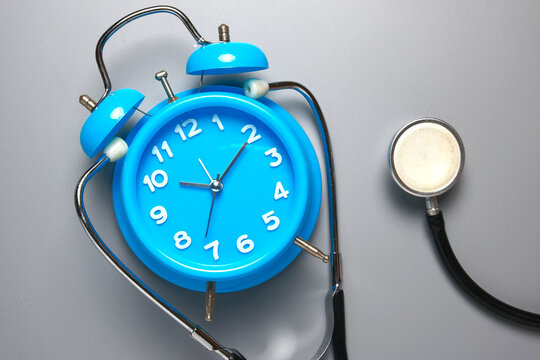 A picture of clock and stethoscope on grey background. Healthcare check up time.