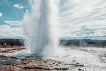 Closeup shot of an active outbreak geyser against blue sky background