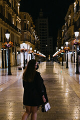 Fototapeta na wymiar Chica guapa caminando por las calles nocturnas de Málaga