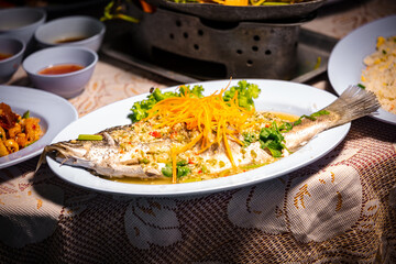Steamed sea bass fish with lemon, Thai famous local food served on fish shape plate. Thai recommend menu for tourist. Steamed fish with herb and lemon, topped with spicy sour sauce. PLA NERNG MANAW.