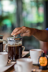 Hand preparing coffee in French Press Coffee Maker. Morning concept. coffee siphon. Spent coffee break at the organic cafe and prepare Chocolate or tea in French press.
