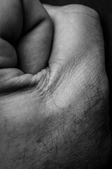 Black and white detail of a male hand making a fist with folds and skin texture