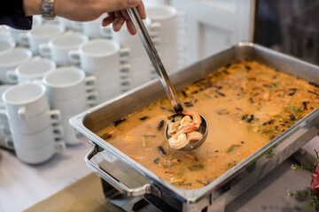 Food Buffet Catering Dining Eating Party Sharing Concept. hand hold River prawn spicy soup on buffet line. Buffet food indoor in luxury restaurant .