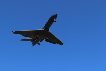 Fototapeta na wymiar Avión negro aterrizando en el aeropuerto con el fondo del cielo azul