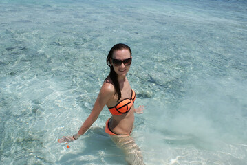 A young woman is resting and swimming in the ocean on a paradise island.