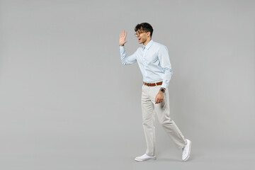 Fototapeta na wymiar Full length side view fun young successful employee business latin man corporate lawyer wear classic white shirt glasses walking waving hand greeting isolated on grey background studio Career concept.