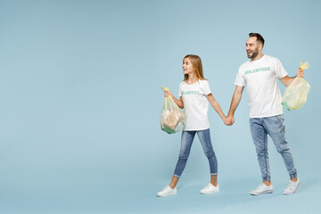 Obraz premium Full length two young friends couple teen girl man wear white tshirt green volunteer hold bag trash walk isolated on pastel blue color background Voluntary free team work help charity grace concept