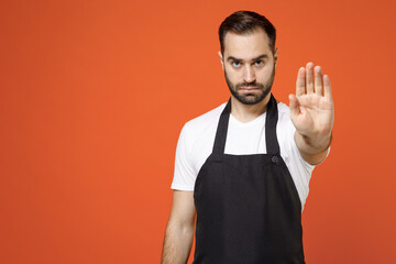 Young surprised man 20s barista bartender barman employee in black apron white t-shirt work in...