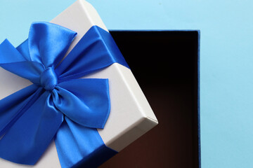 Open gift box with blue ribbon on blue paper background. Fathers day present for dad. Top view, copy space