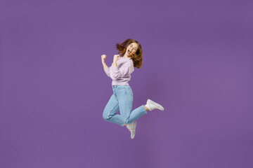 Full length side view young excited overjoyed happy woman 20s in purple knitted sweater jump high...