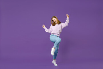 Fototapeta na wymiar Full length young overjoyed happy student caucasian woman in purple sweater do winner gesture point finger up with raised up leg isolated on violet background studio portrait People lifestyle concept.