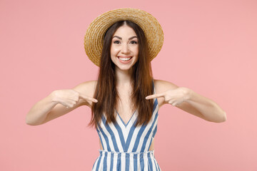 Young excited surprised smiling caucasian woman in summer clothes striped dress straw hat point...