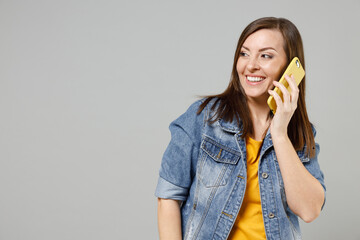 Young smiling friendly woman 20s wear in trendy denim jacket yellow t-shirt talking on mobile cell...