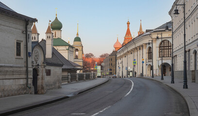 Early morning in Moscow. Empty street with lanterns and ancient churches. Red Square in the distance. Clear sky