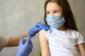 Vaccination of kid from COVID-19 or flu, cute little girl in mask during corona virus vaccine...