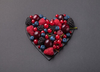 Berries fresh heart shaped ready to eat healthy food vibrant overhead assorted arrangement on dark gray background studio shot
