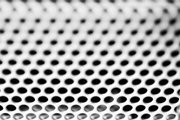 White ventilation grille. Round holes. Metal construction. Dark background. Close-up view. Black and white tones.