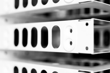 Metal frame construction. Several metal compartments for equipment. Oval holes. Dark background. Front view close-up. Black and white tones.