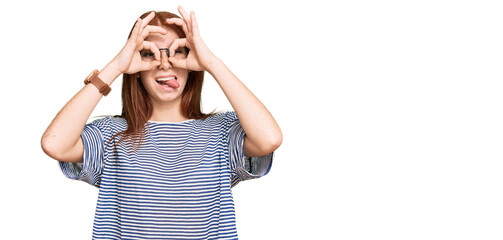 Young read head woman wearing casual clothes and glasses doing ok gesture like binoculars sticking...