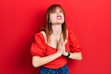 Redhead young woman wearing casual red t shirt begging and praying with hands together with hope expression on face very emotional and worried. begging.
