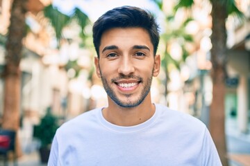 Young latin man smiling happy walking at the city.