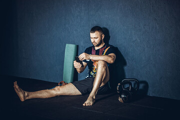 Fitness man looking to the phone for motivation before gym workout. Sporty male athlete looking his smartphone.