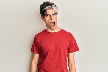 Young hispanic man wearing casual clothes in shock face, looking skeptical and sarcastic, surprised...