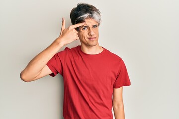 Young hispanic man wearing casual clothes pointing unhappy to pimple on forehead, ugly infection of...