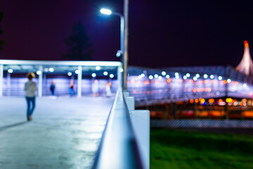 Pedestrian bridge with lanterns. People go on the road. Night in the city. Close up view from the...